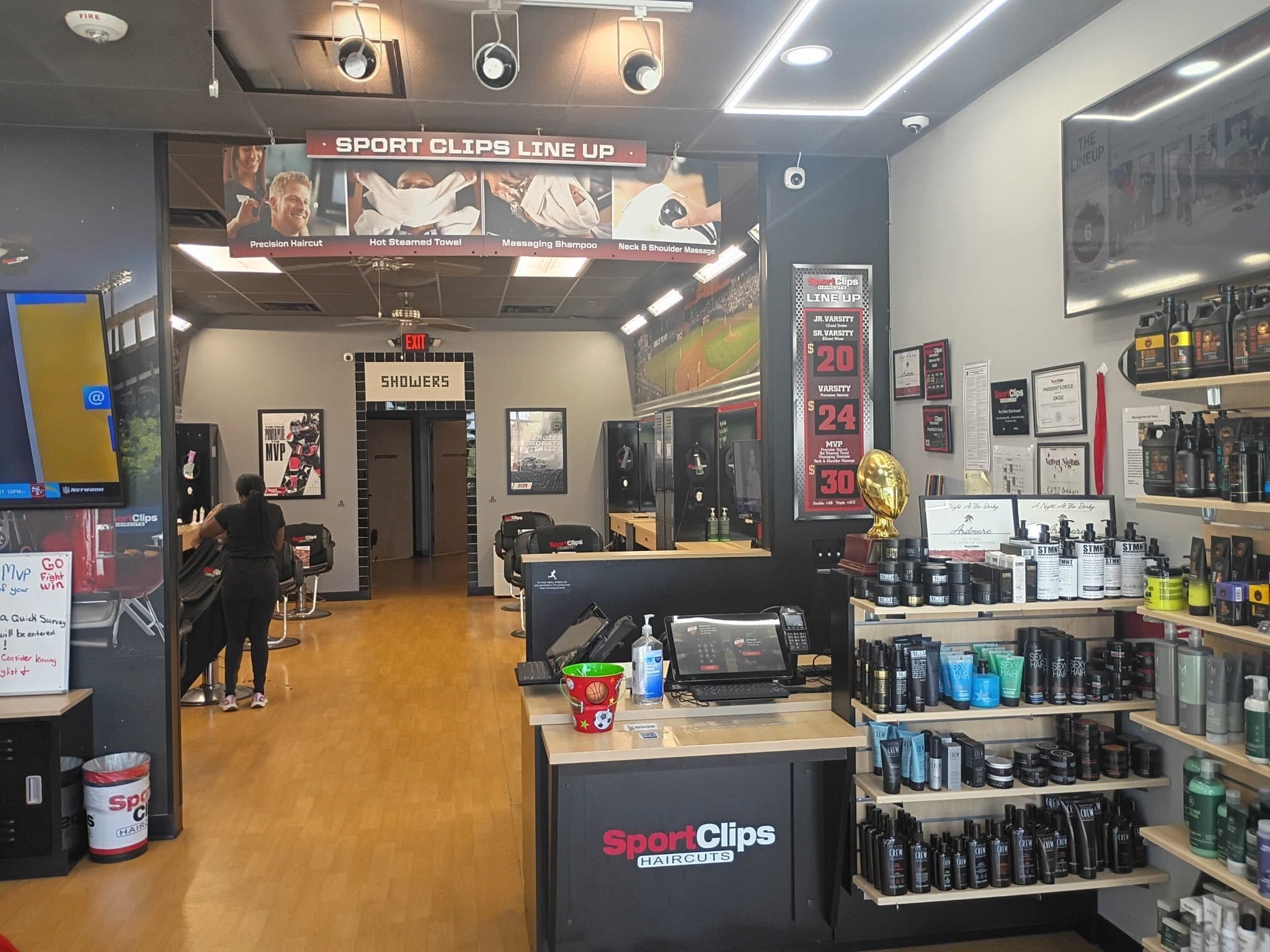 Front counter of a Sport Clips Haircuts salon, with a stylist at work